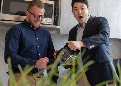 Two team members laughing over coffee in the office.